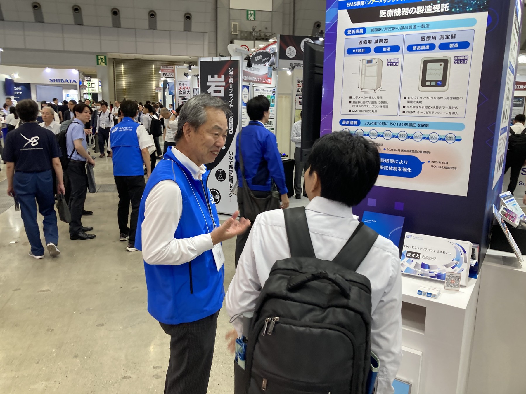 会長の八巻もブースに立ちパネルを用いて医療機器の製造受託について説明